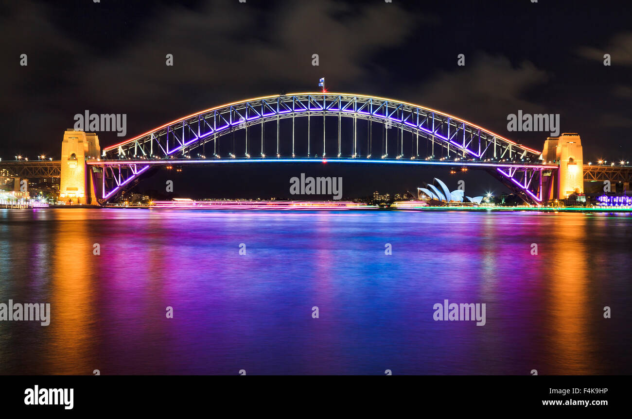 Australia Sydney Harbour Bridge side view of illuminated arch after sunset with bright refiection of the lights in blurred water Stock Photo