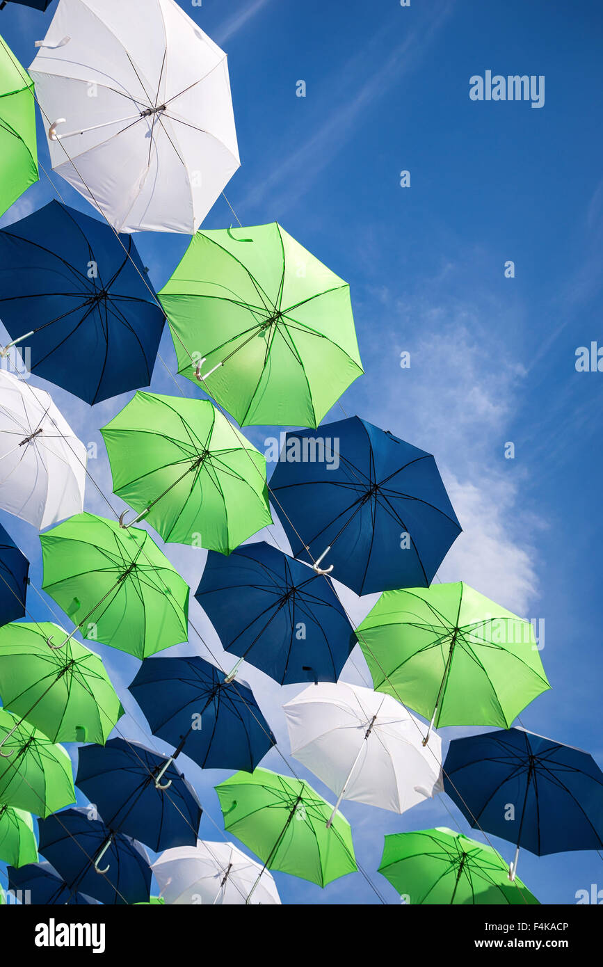 Group of green, blue, and white umbrellas against blue sky Stock Photo