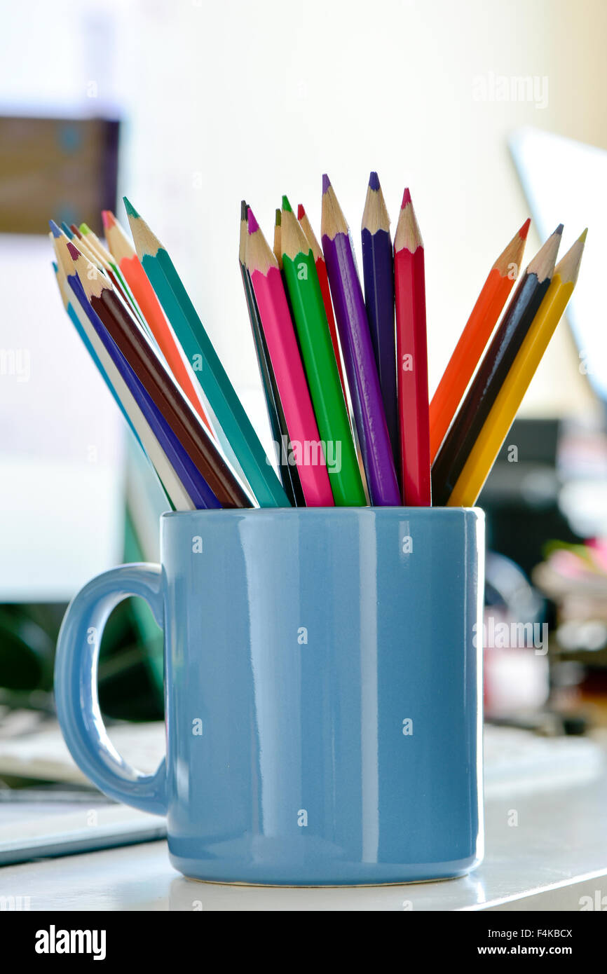 closeup of a blue mug with many coloured pencils of different colors, on a desk Stock Photo