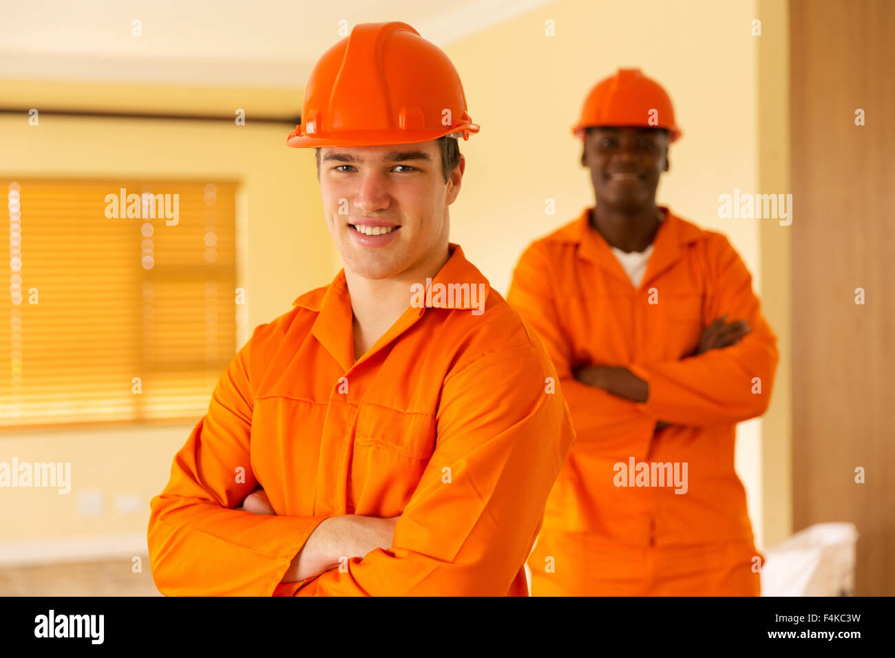 happy co-workers standing inside house under construction Stock Photo
