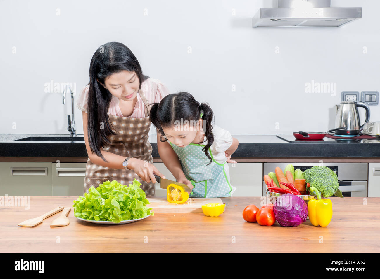 family, children and happy people concept - Asian mother and kid daughter cooking in the kitchen at home Stock Photo