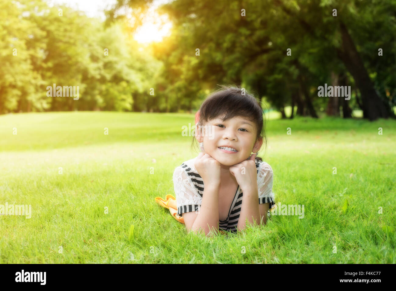 Little asian girl laying down on the green grass Stock Photo