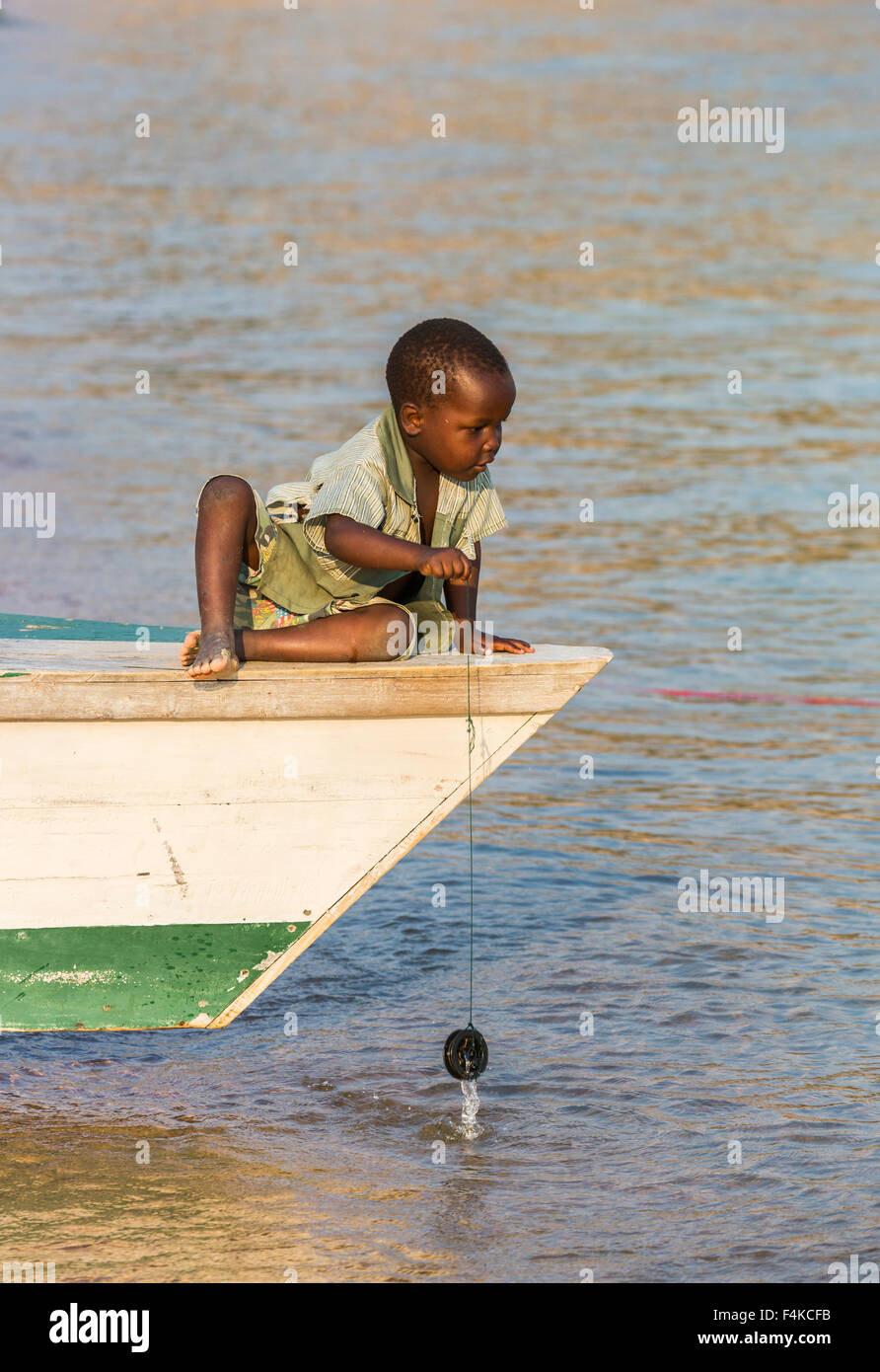 Local African boy playing at fishing from a fishing boat, Kaya Mawa, Likoma Island, Lake Malawi, Malawi, south-east Africa Stock Photo