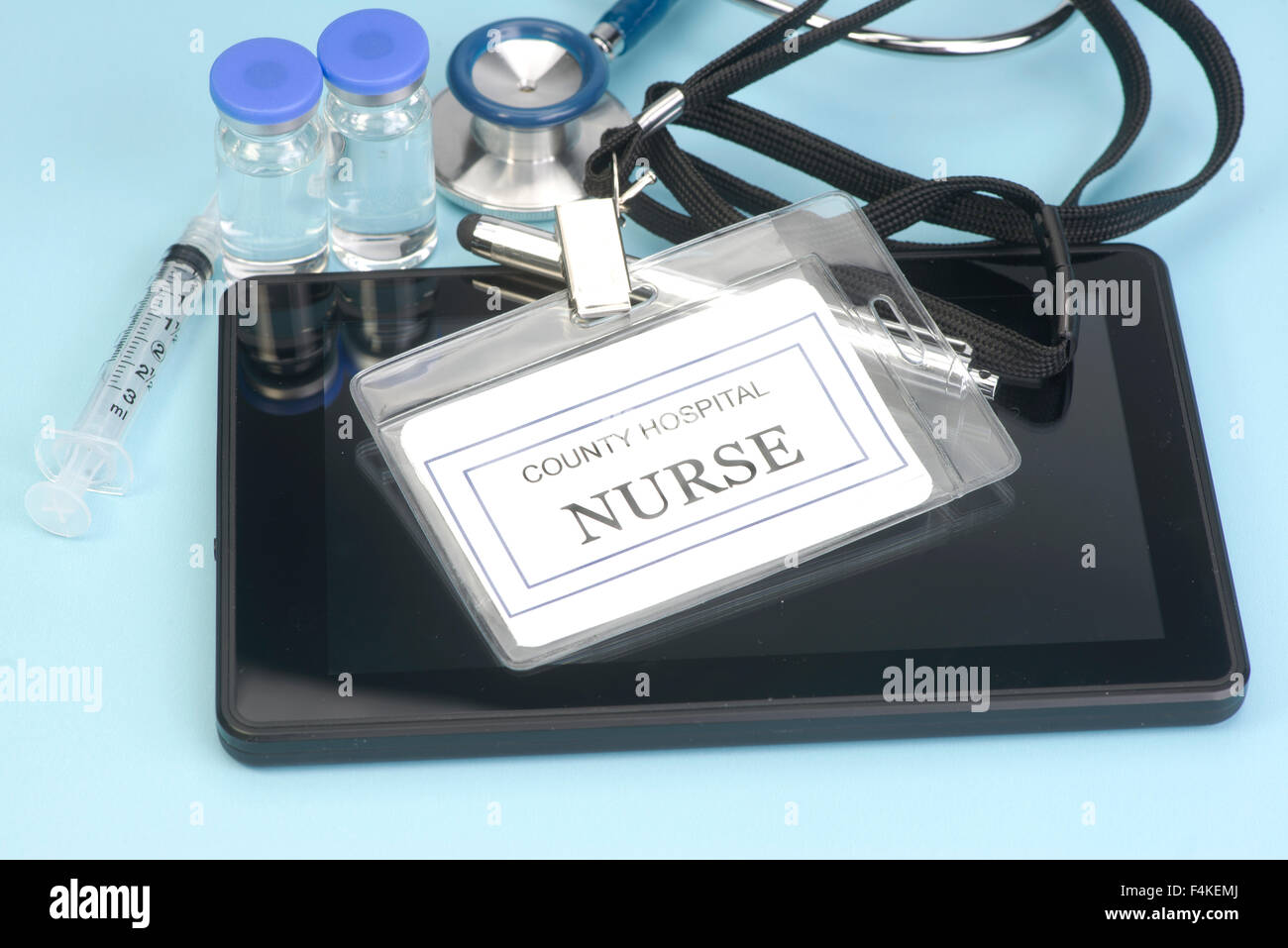 Fictitious nurse identification tag on personal computing device with stethoscope and vials. Stock Photo