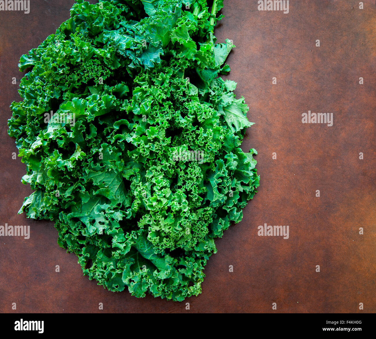 Bunch of fresh raw green kale plant on brown table Stock Photo