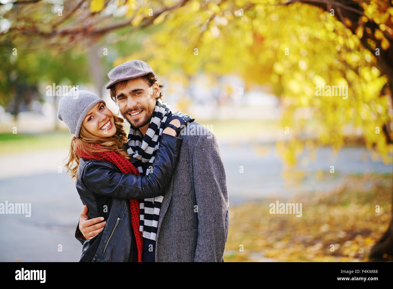 Romantic couple looking at camera in autumn park Stock Photo - Alamy