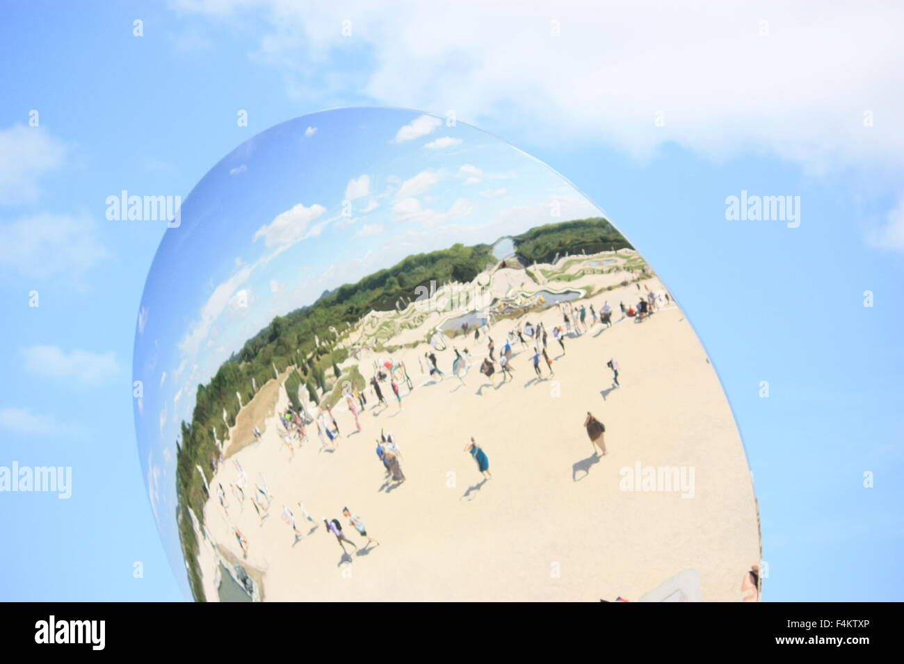 Reflections of unidentified tourists in the spherical mirror Stock Photo
