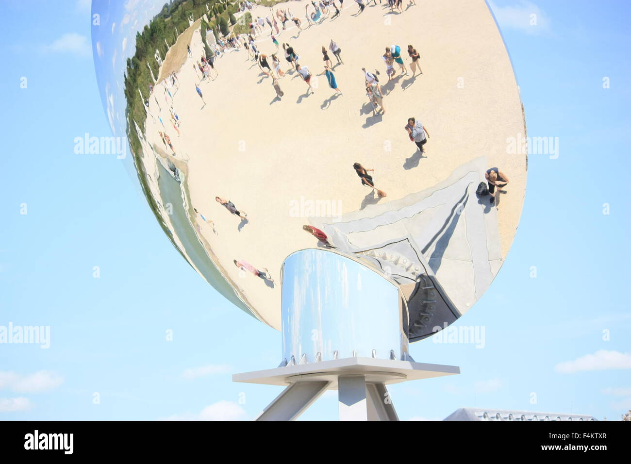 Reflections of unidentified tourists in the spherical mirror Stock Photo