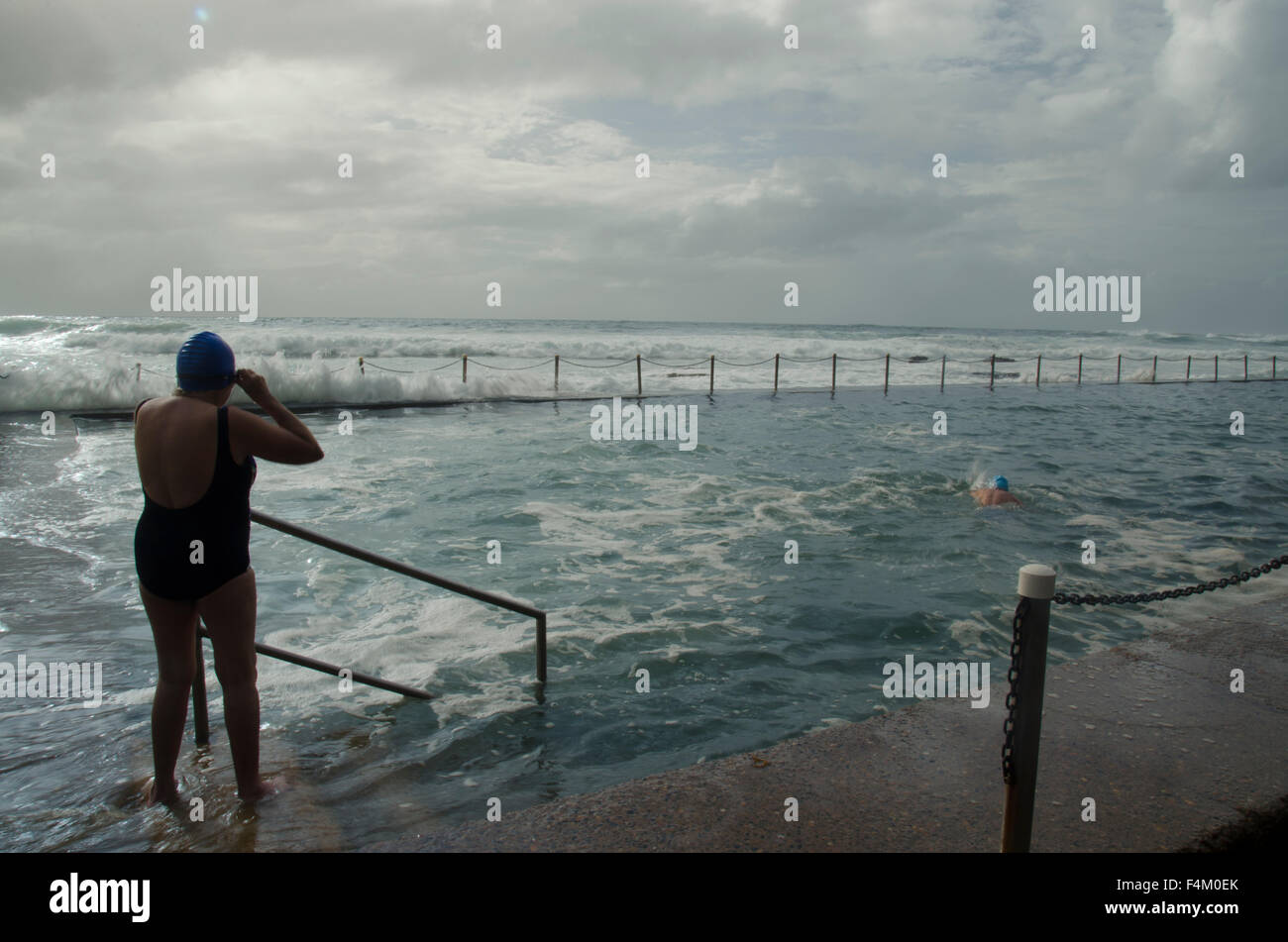 Older woman preparing to swim in rough sea conditions at Newport Beach ocean pool in Sydney, Australia Stock Photo