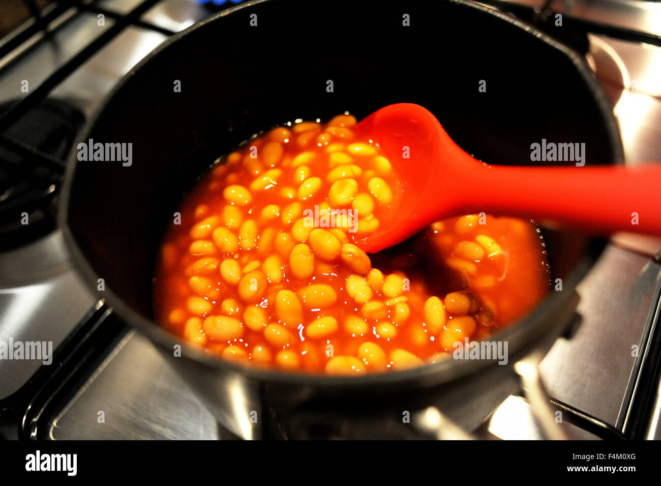 Baked beans being warmed up in a saucepan on a gas hob Stock Photo Alamy