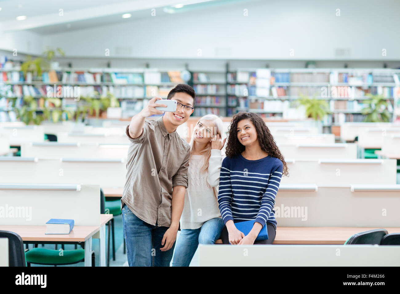 Portrait of a happy multi ethnic students making selfie photo on smartphone in the university library Stock Photo