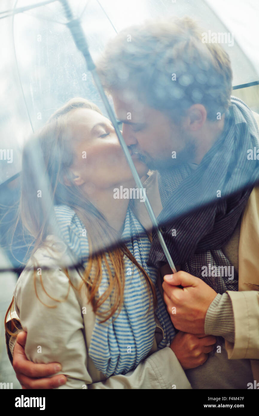 Amorous man and woman kissing under umbrella Stock Photo - Alamy
