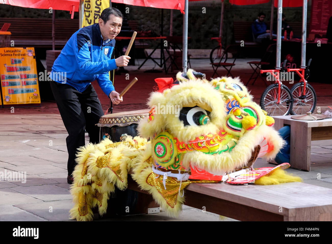 Chinese man drumming with traditional dragon costume lying on bench next to him Stock Photo