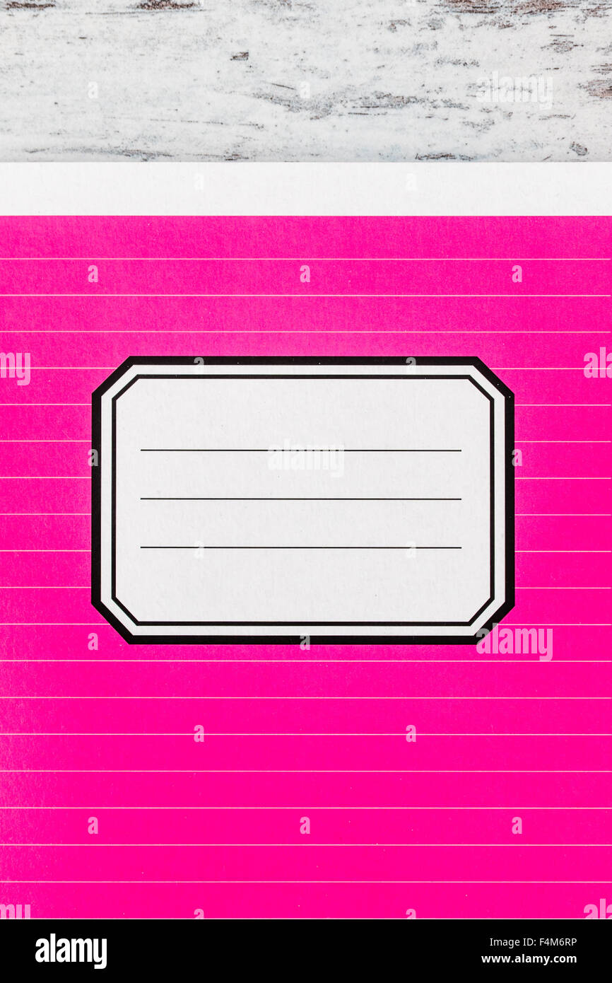 Pink notebook with name label on cover on white wooden background, copy ...