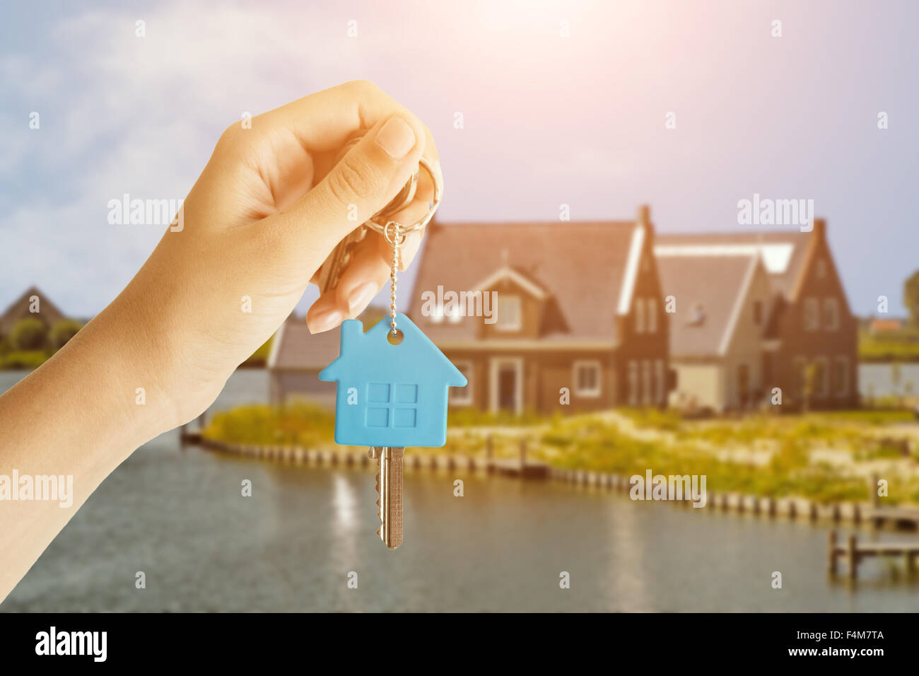 Woman Handing Over the House Keys in Front of a Beautiful New Home. Stock Photo