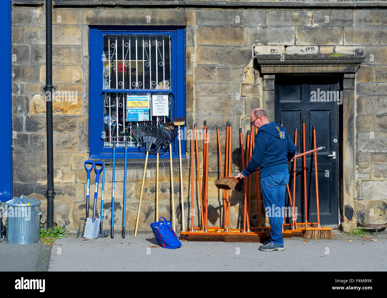Man choosing a broom outside a shop in Otley, West Yorkshire, England UK Stock Photo