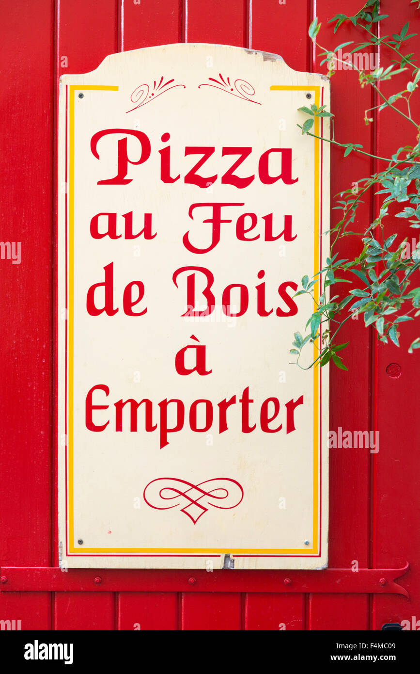 A sign advertising a wood fired pizza restaurant and takeaway in Provence France. Pizza au Feu de Bois a emporter Stock Photo