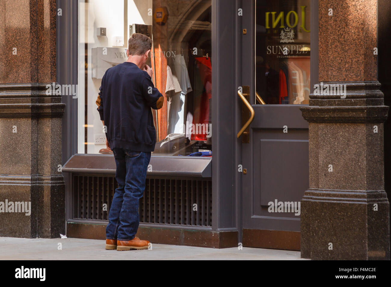 Man stops to look in clothing shop window on Jermyn Street, London. He