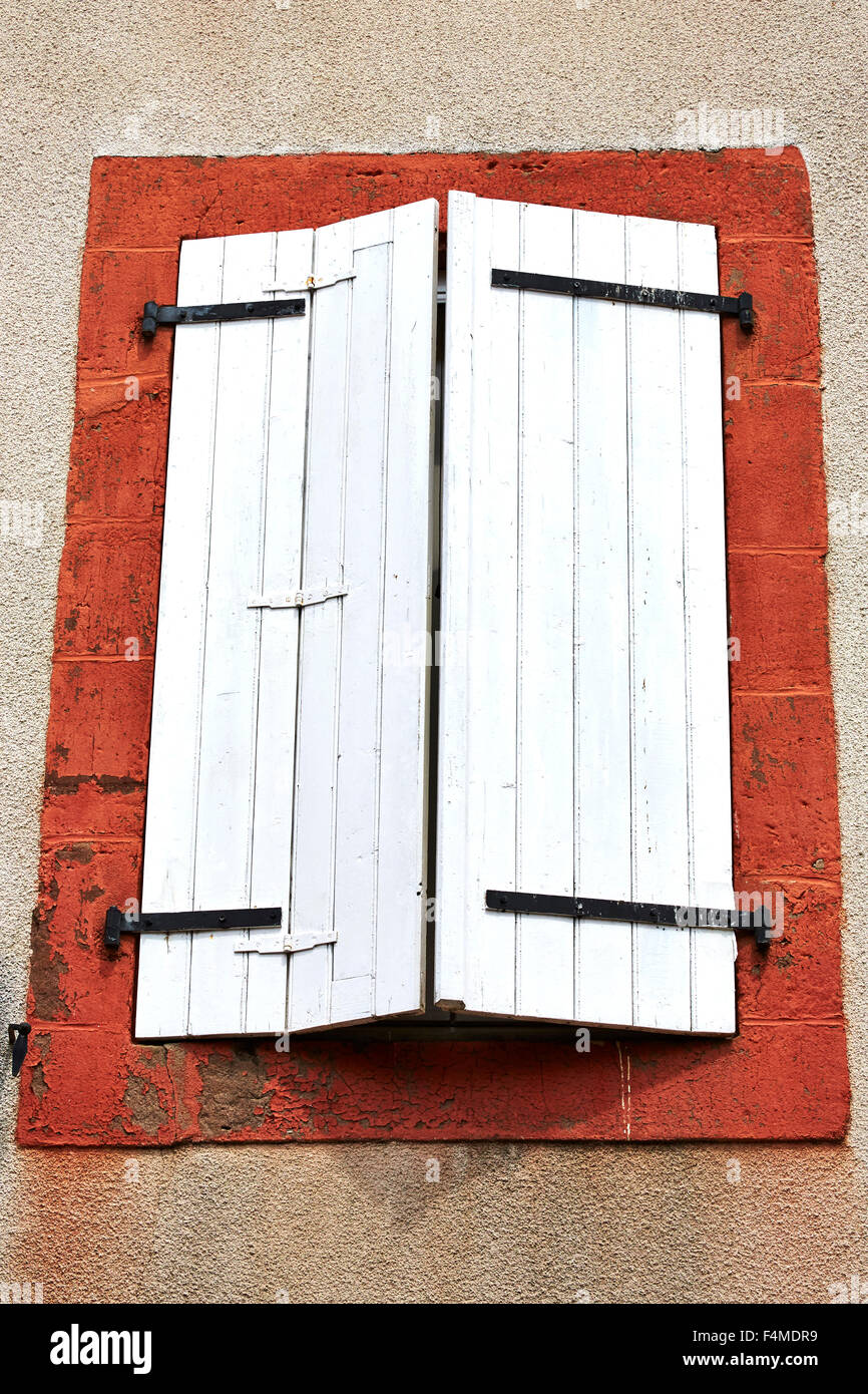 Window with white shutters and a red frame in the village of Saint-Robert, Correze, Limousin, France. Stock Photo