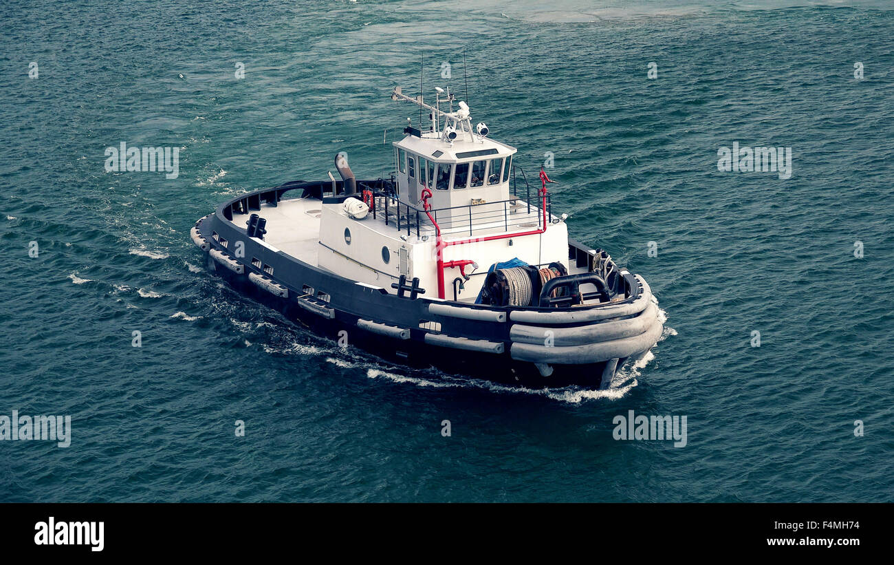 A tugboat prepares to guide ship out of the harbor near Lahaina on the island of Maui Stock Photo