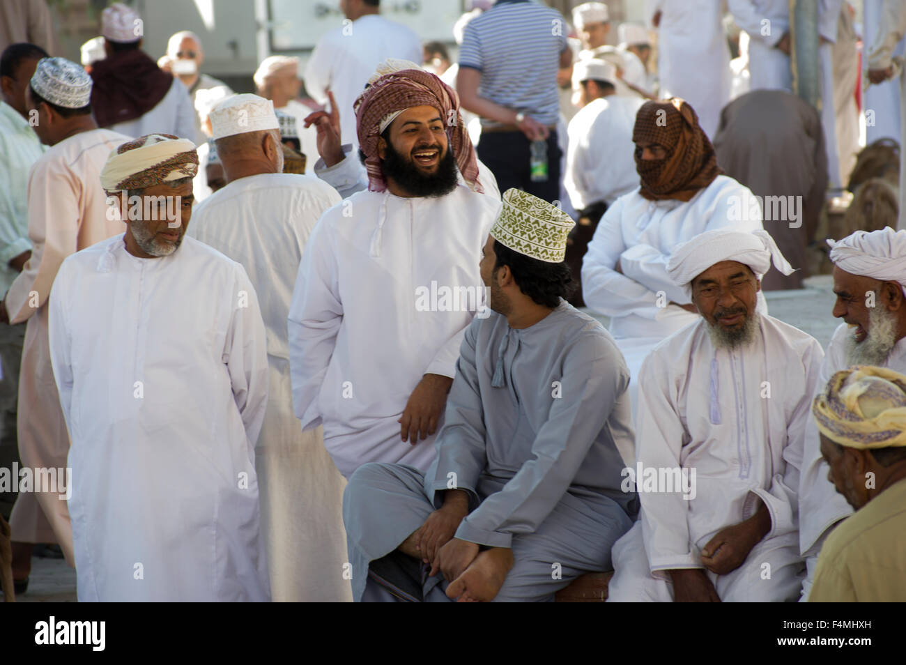 Omani men smiling and laughing watching livestock for sale at the Nizwah Thursday market day. Stock Photo
