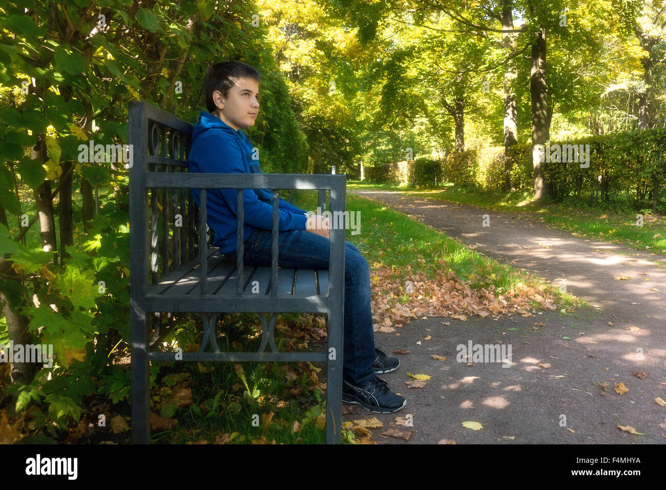 The photo depicts a boy sitting on a bench Stock Photo - Alamy