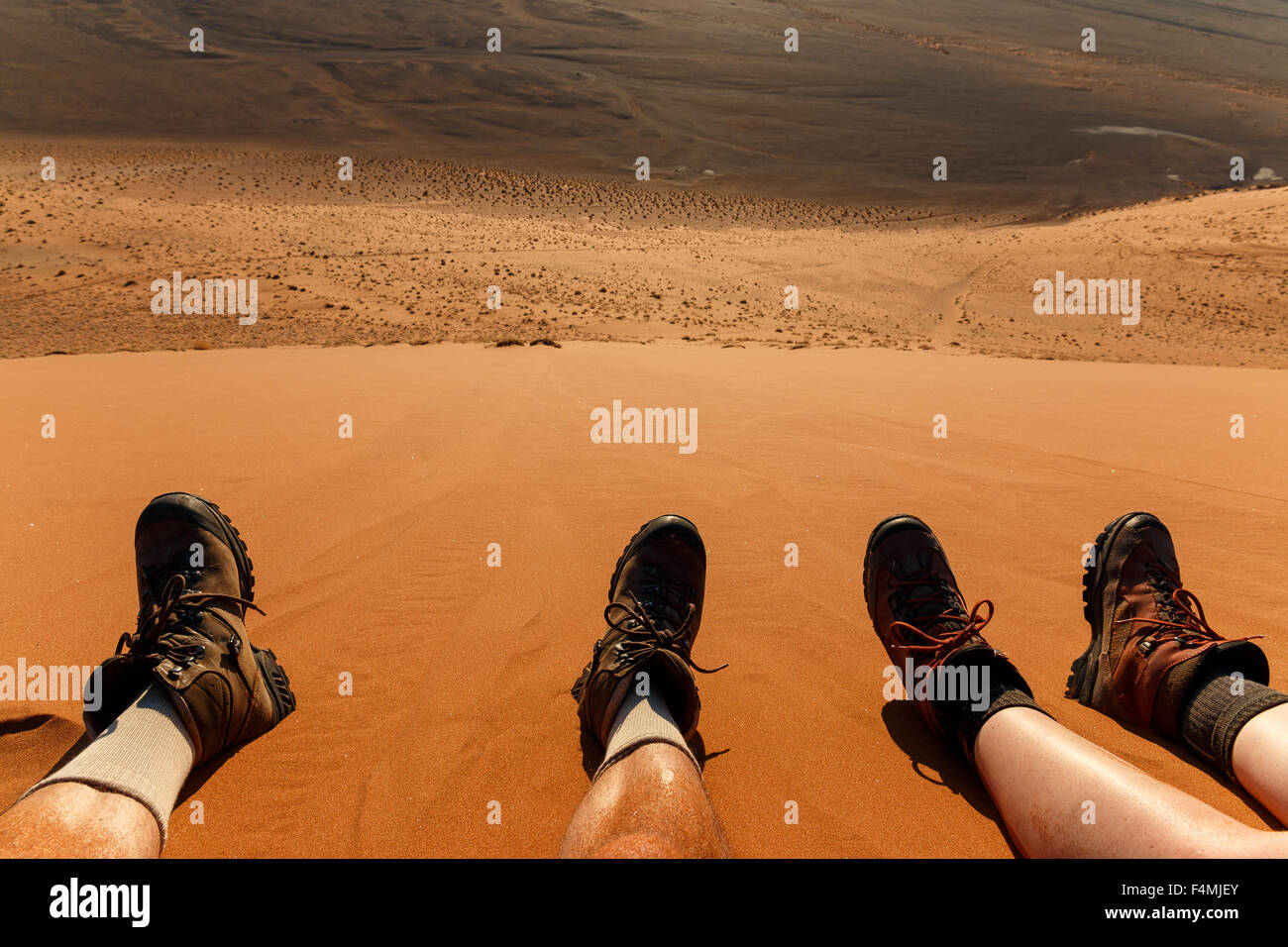 Enjoying landscape and resting after climbing red sand dune in desert. Namibia, Sossusvlei, Naukluft, Africa. Stock Photo