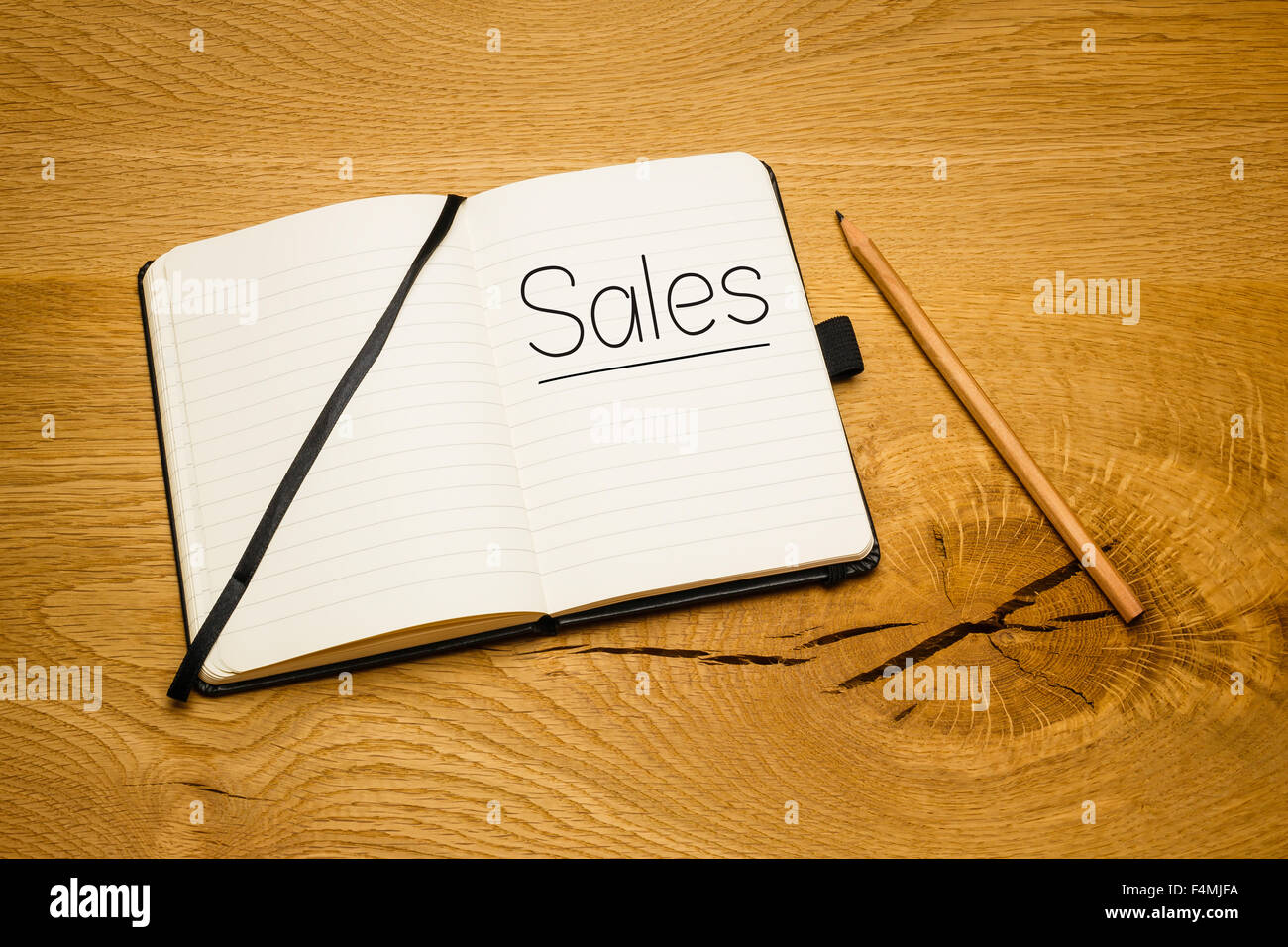 Notebook on office desk with sales text written with pencil. Stock Photo
