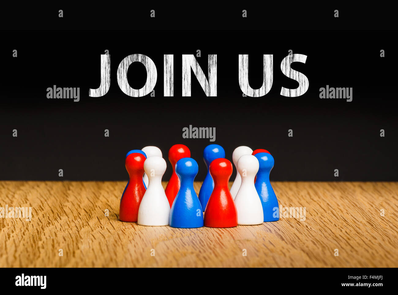 Concept for join us, join our team with white chalk text. Red white blue pawn figures and black background on oak. Stock Photo