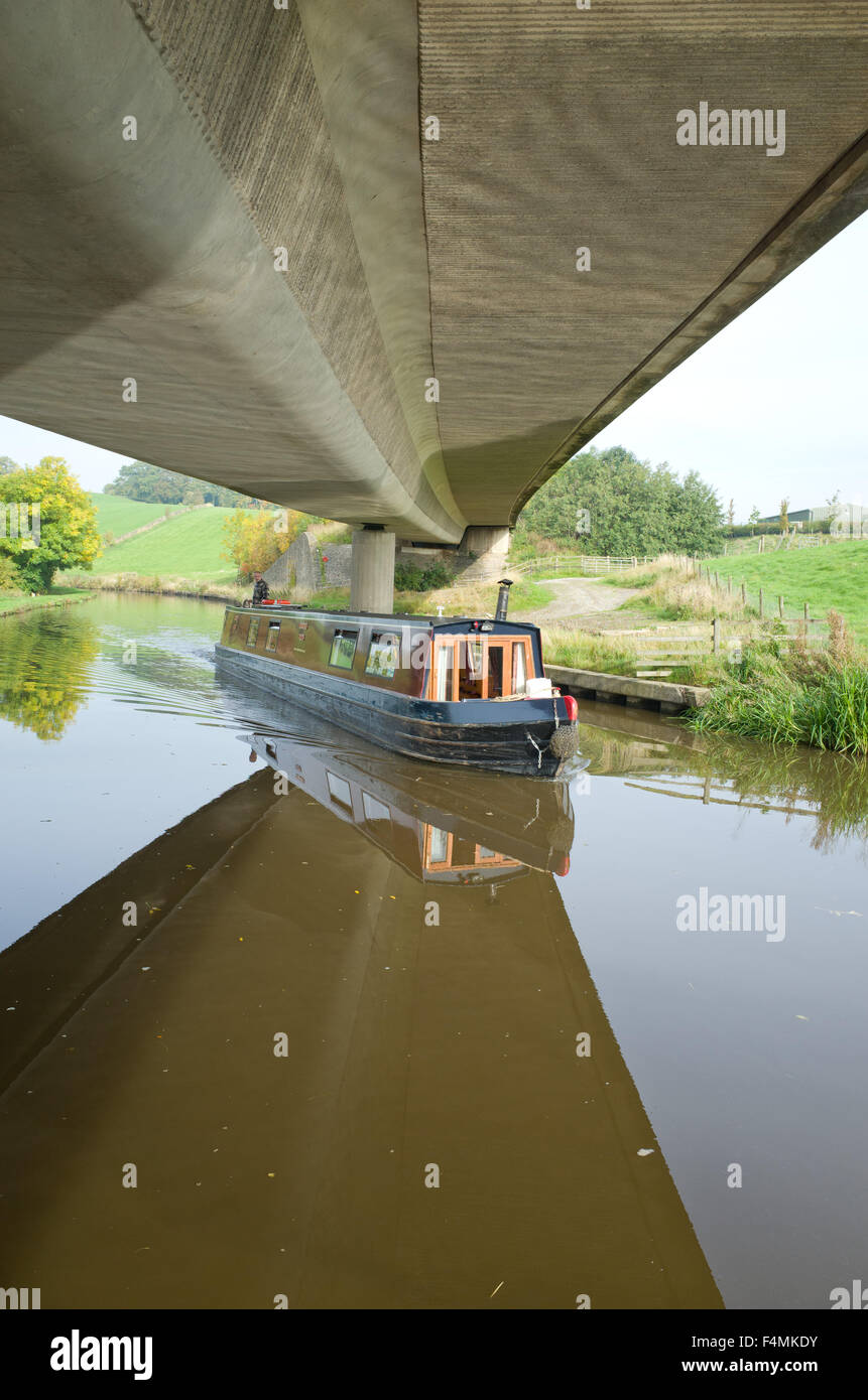 Canal narrow boat passing under road bridge, Leeds Liverpool Canal Skipton UK Stock Photo