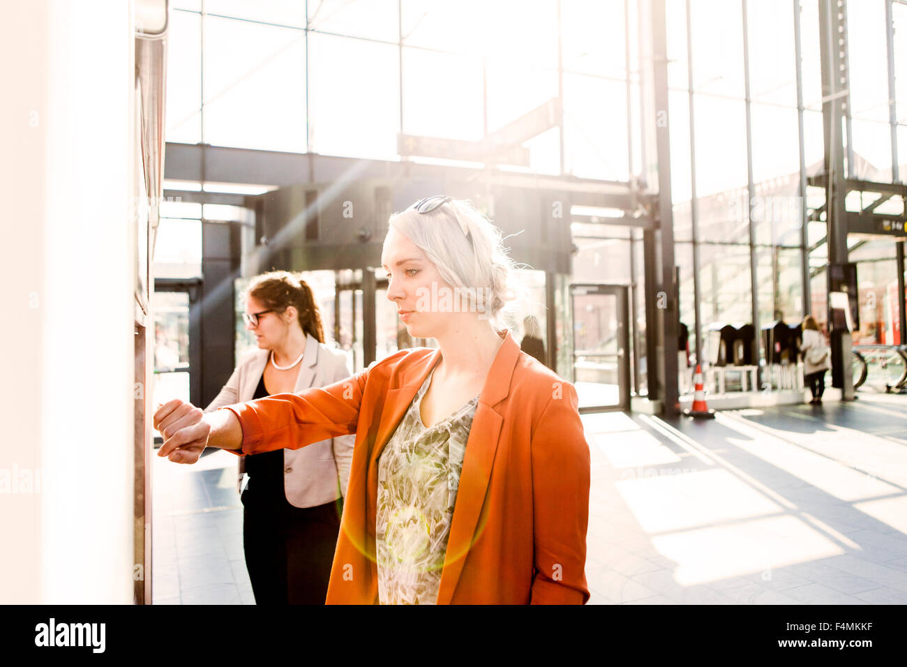 Businesswomen using ticket machine at railroad station Stock Photo - Alamy