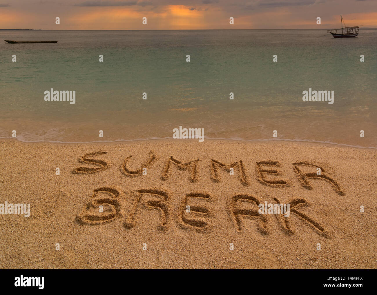 In the picture a beach at sunset with the words on the sand 'Summer break'. Stock Photo