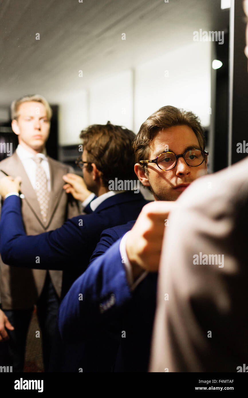 Salesman adjusting customer's suit in fitting room at clothing store