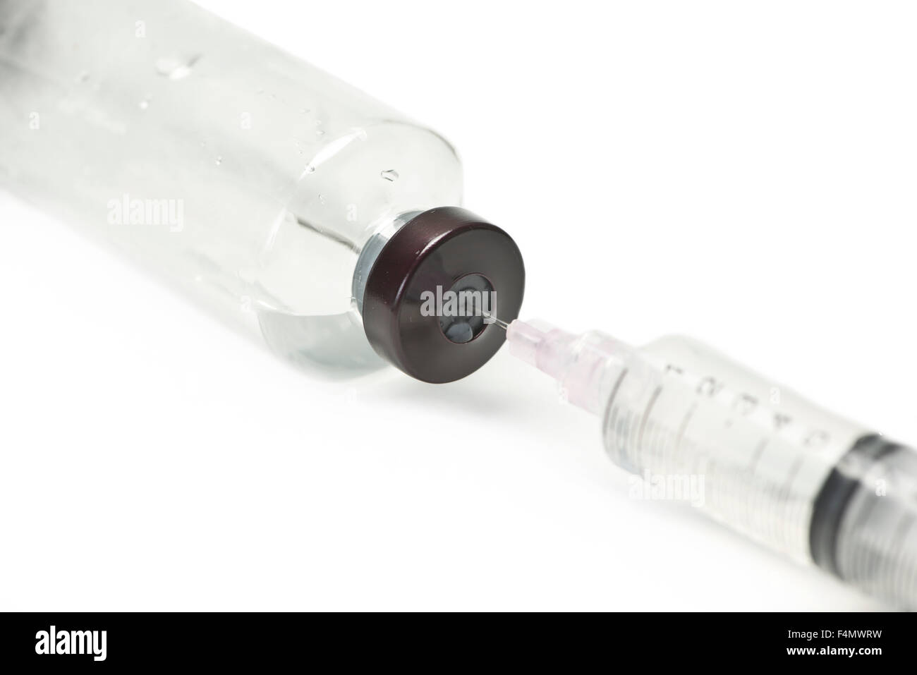 Syringe draws liquid from large clear vial. Stock Photo