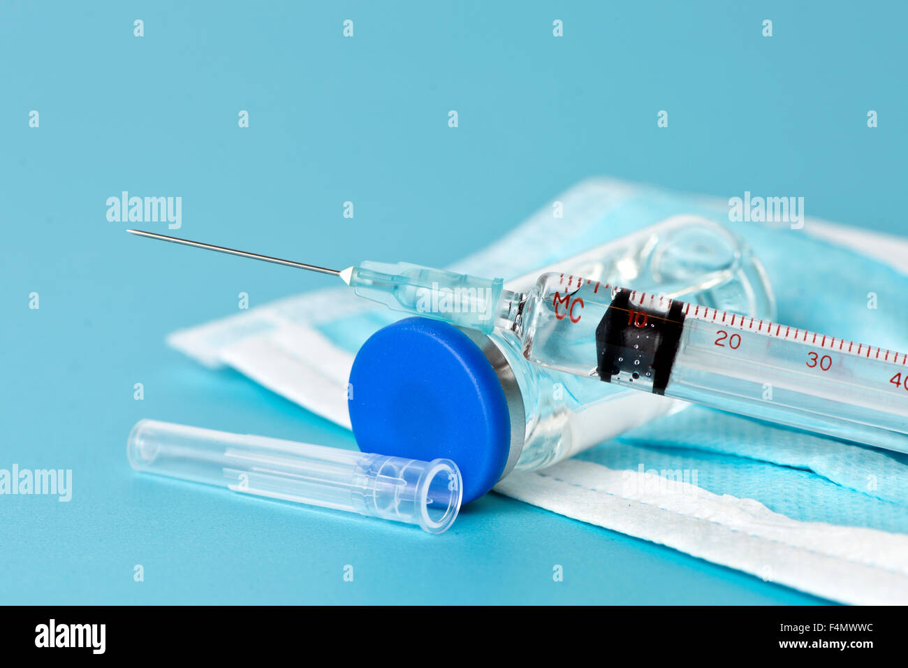 Syringe and medication vial with mask on blue background Stock Photo ...