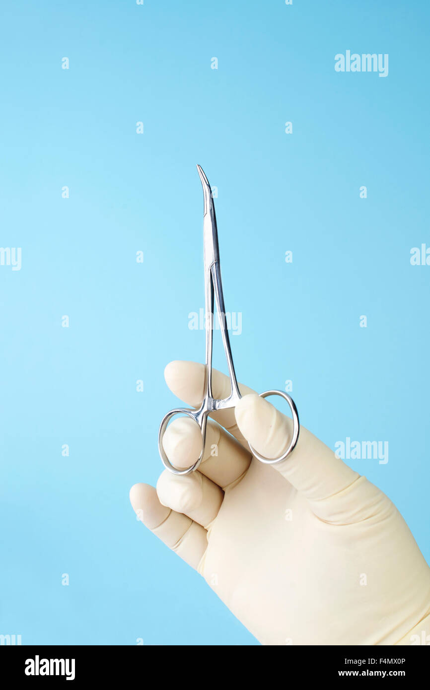 Surgeon holding small curved hemostats on blue background Stock Photo Alamy