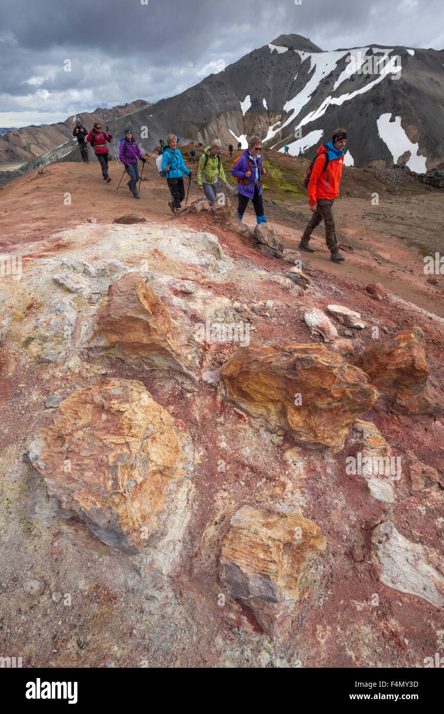 Hikers passing volcanic mineral deposits at Landmannalaugar, Sudhurland, Iceland. Stock Photo
