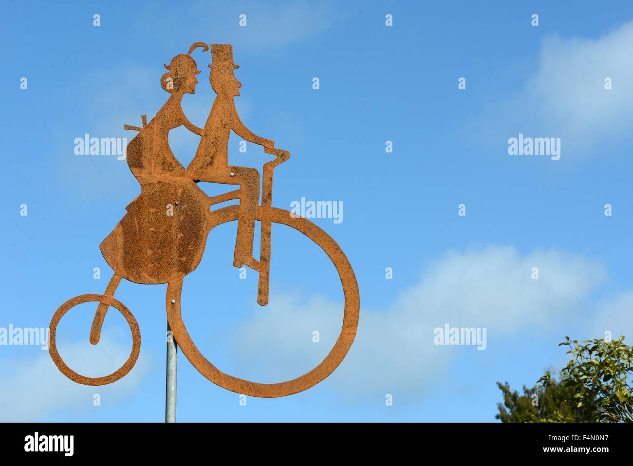 Rusty silhouette of a man and woman riding a penny farthing bicycle Stock Photo