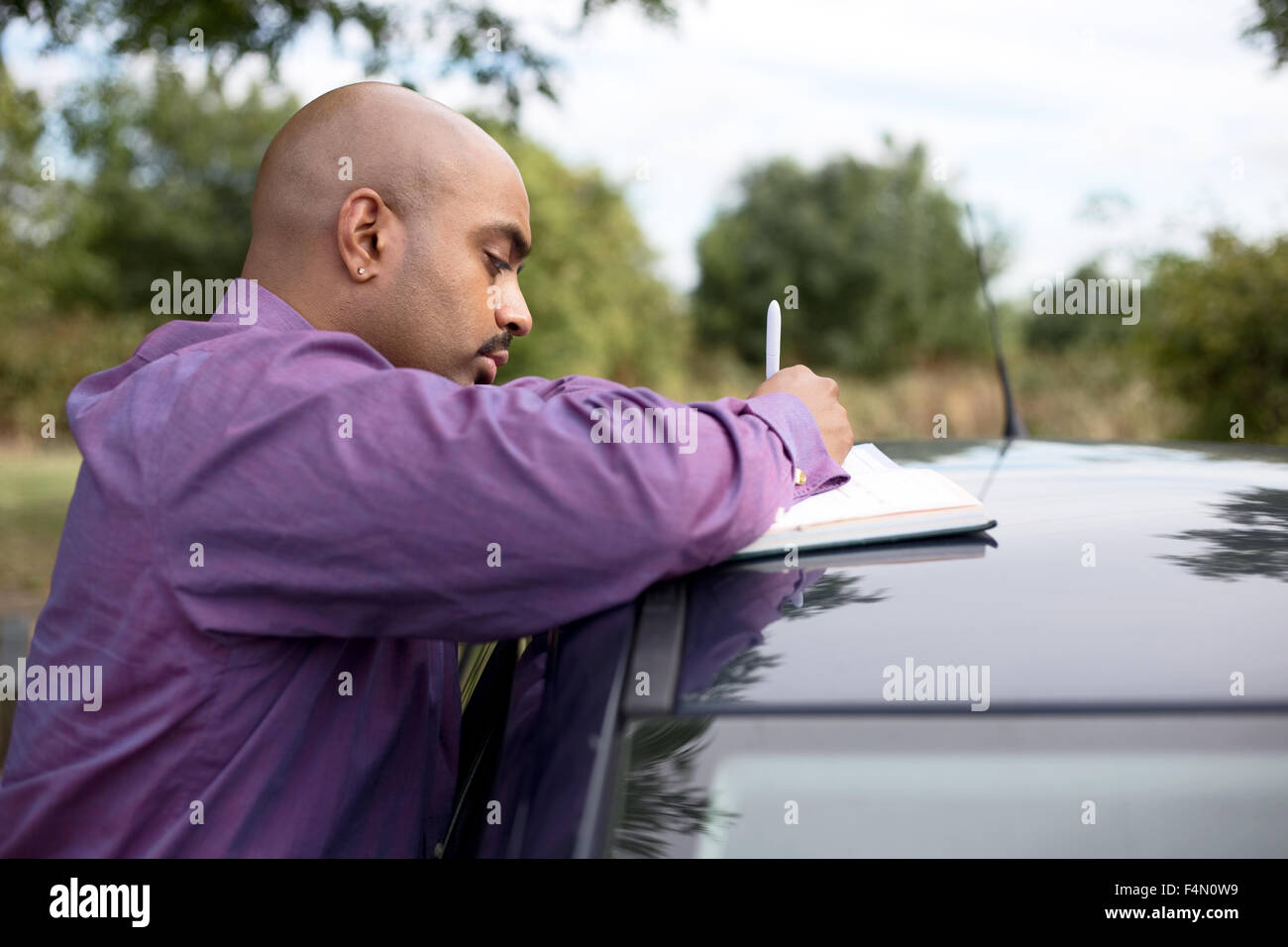 man writing notes on his car roof Stock Photo