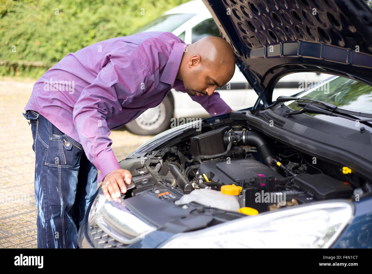 man looking at the engine of his car Stock Photo