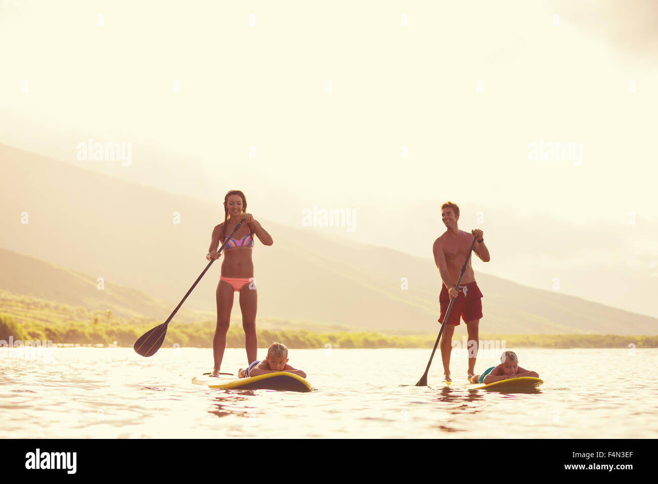 Family stand up paddling at sunrise, Summer fun outdoor lifestyle Stock Photo