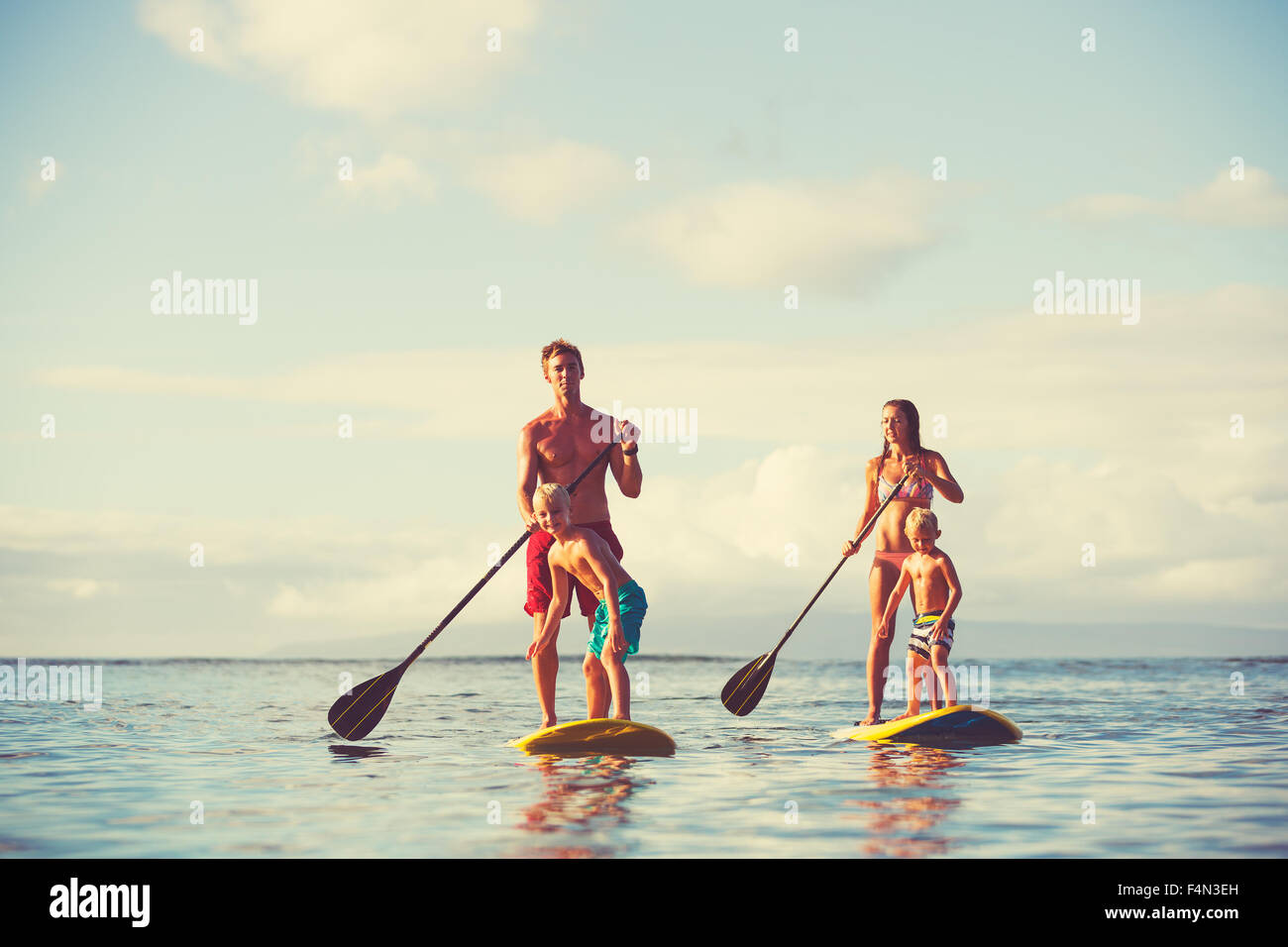 Family stand up paddling at sunrise, Summer fun outdoor lifestyle Stock Photo