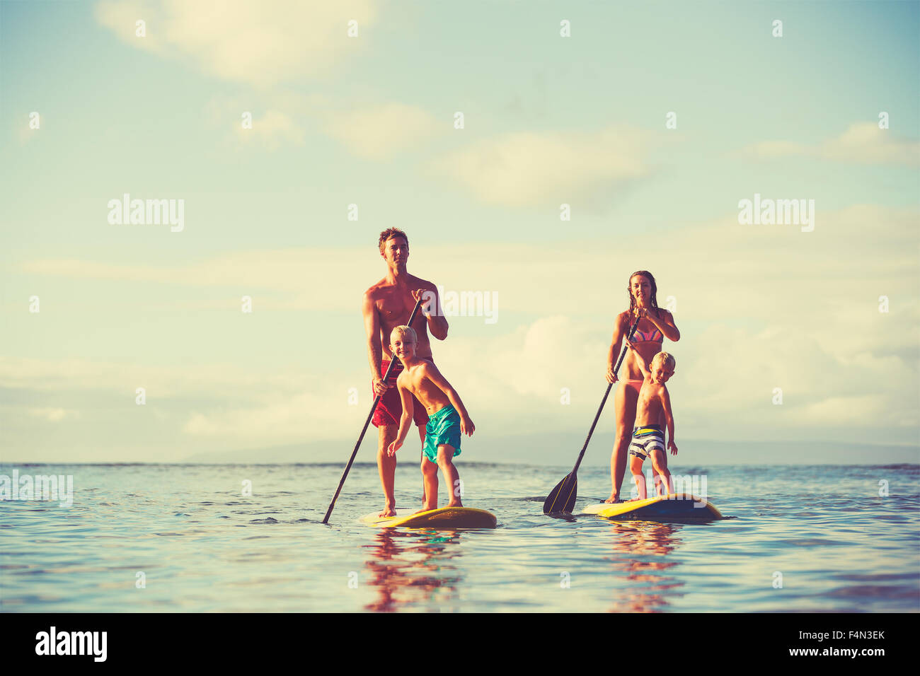 Family stand up paddling at sunrise, Summer fun outdoor lifestyle Stock Photo