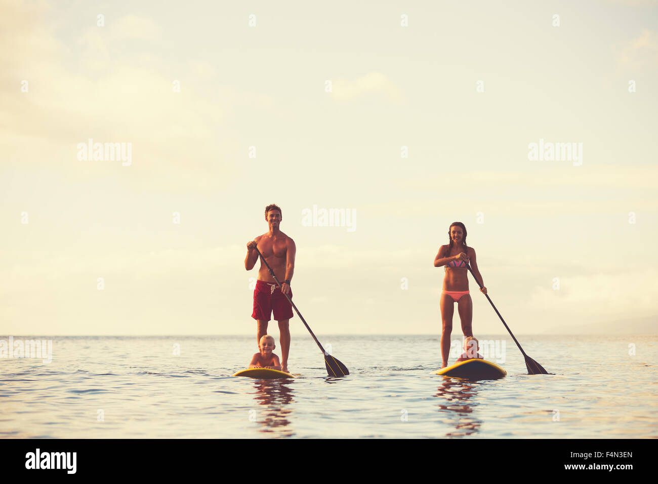 Family stand up paddling at sunrise, Summer fun outdoor lifestyle Stock Photo