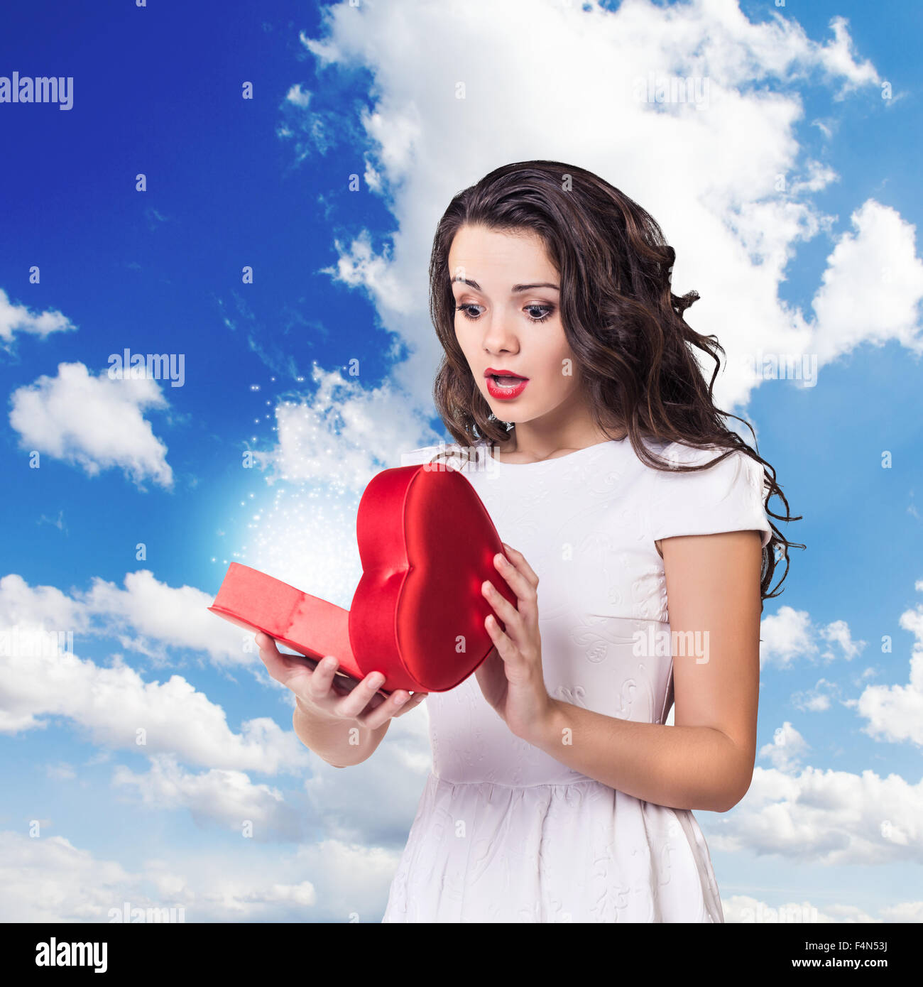 Young surprised woman holds open heart box Stock Photo