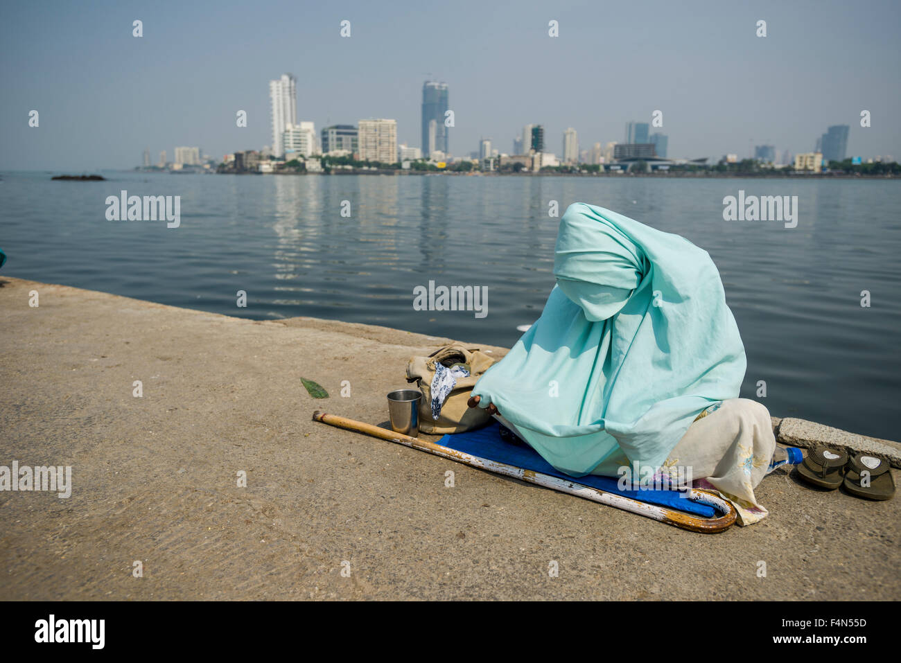 A muslim woman in a burka is begging for money on the walkway to the Haji Ali Dargah, the tomb of the Muslim Saint Pir Haji Ali Stock Photo