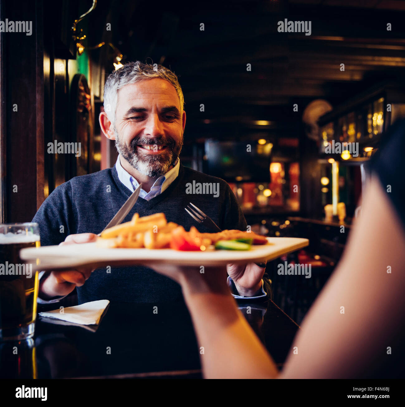 Smiling man in restaurant receiving Wiener Schnitzel with French fries ...