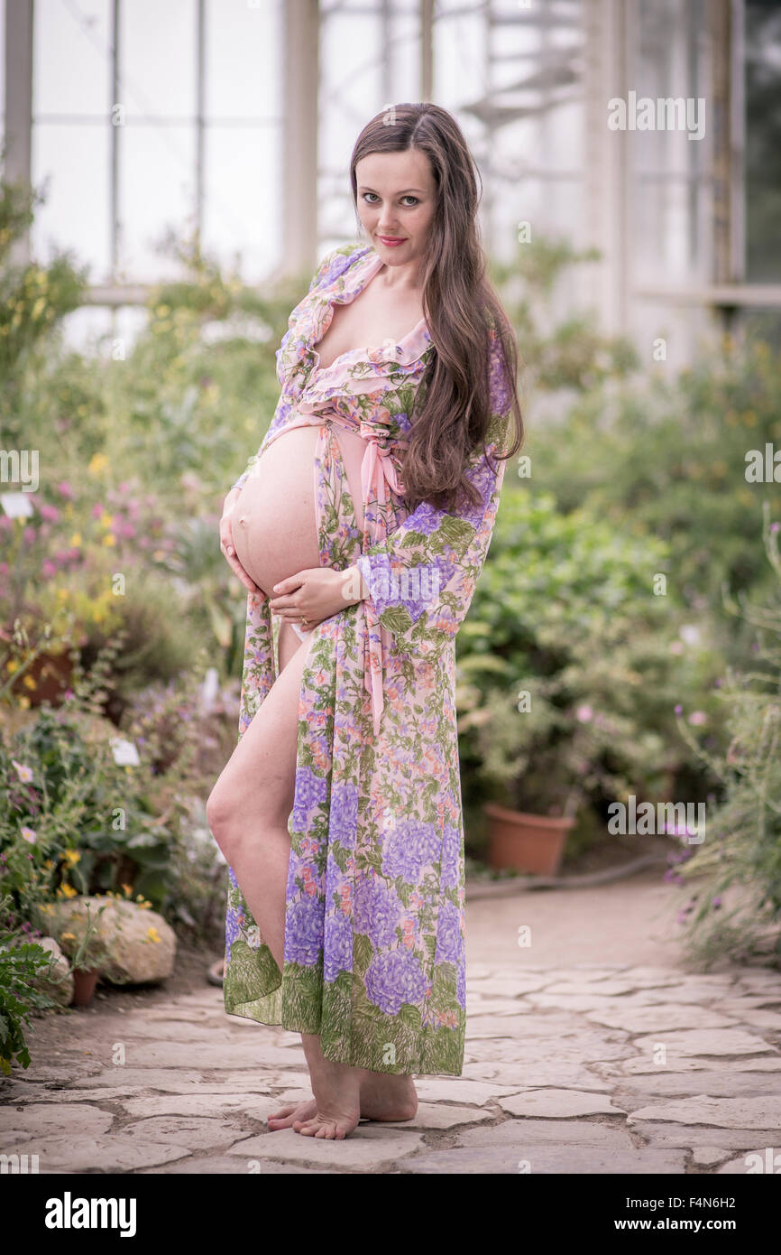 Portrait of pregnant woman wearing fashionable bathrobe holding her