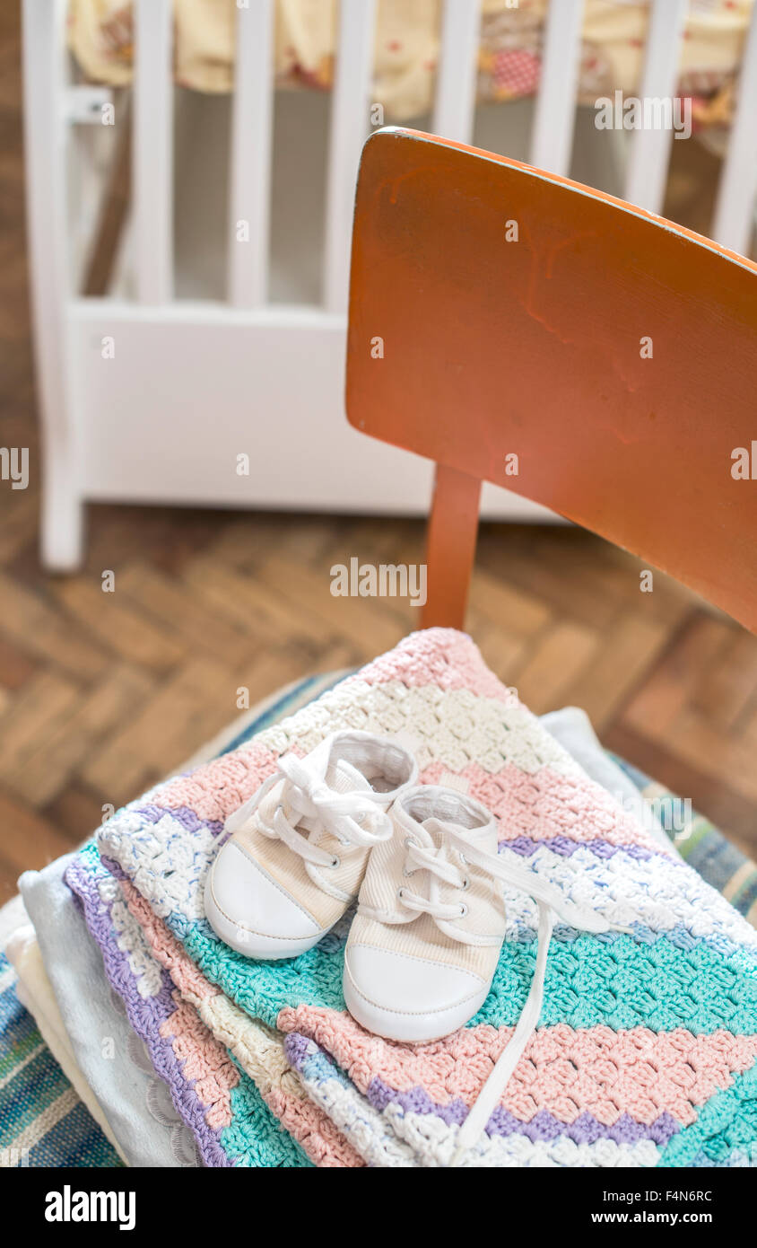 Stack of blankets and baby shoes on a chair Stock Photo Alamy