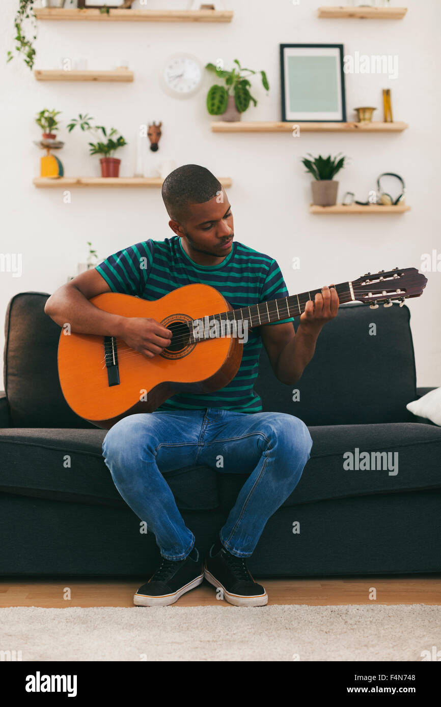 Man sitting on a couch playing guitar Stock Photo - Alamy